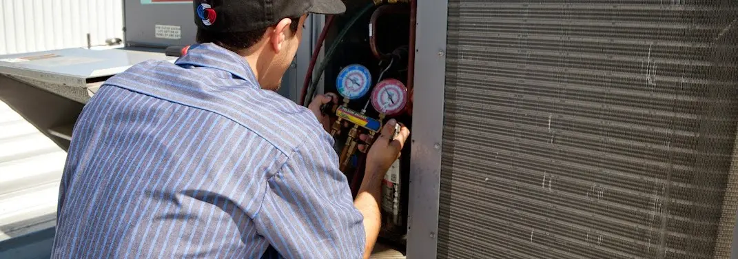HVAC technician servicing a condenser unit in Pearsall