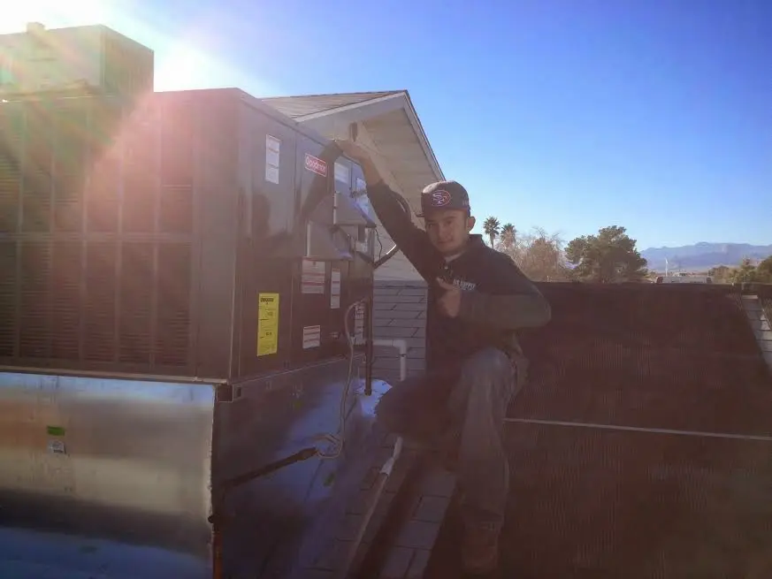 HVAC technician performing AC Tune-Up on a rooftop unit in Pearsall
